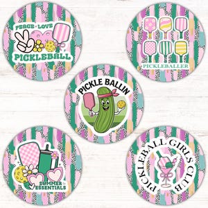 Pode incluir: Cinco adesivos redondos com fundo abstrato verde, rosa e branco. Os adesivos apresentam designs com tema de pickleball com texto que diz "Peace Love Pickleball", "Pickle Ballin", "Pickleballer", "Summer Essentials" e "Pickleball Girls Club".