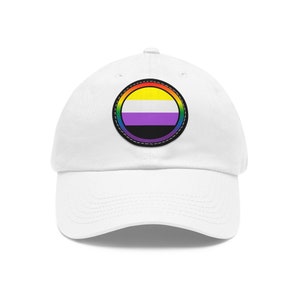 Könnte beinhalten: Weiße Baseballkappe mit einem runden Patch, der einen Regenbogenrand und eine gelb-weiß-lila-schwarze gestreifte Flagge im Inneren trägt.