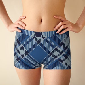 May include: Blue plaid boxer shorts. The shorts have a repeating pattern of intersecting lines in shades of blue, creating a classic plaid design. The waistband is a solid blue, and the shorts are form-fitting.