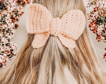 Puede incluir: Una pinza para el pelo con un lazo de ganchillo de color rosa claro. El lazo está atado en una forma clásica con dos lazos y un nudo central.