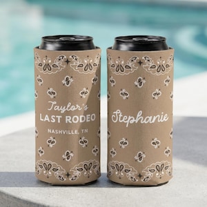 May include: Two tan can coolers featuring a white bandana-style pattern. The left cooler displays the text Taylor's LAST RODEO NASHVILLE, TN in white. The right cooler features the name Stephanie in a white script font. Both have black lids.