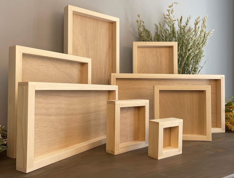Puede incluir: Un conjunto de siete marcos de fotos de madera de diferentes tama&ntilde;os, todos hechos de madera natural con un acabado marr&oacute;n claro. Los marcos est&aacute;n dispuestos en forma escalonada sobre una superficie de madera.
