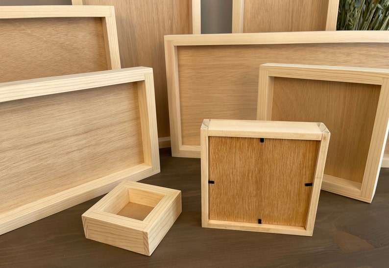 Puede incluir: Un conjunto de cinco marcos de fotos de madera en varios tama&ntilde;os, todos con un acabado de madera natural. Los marcos est&aacute;n dispuestos en un patr&oacute;n escalonado sobre una superficie de madera.