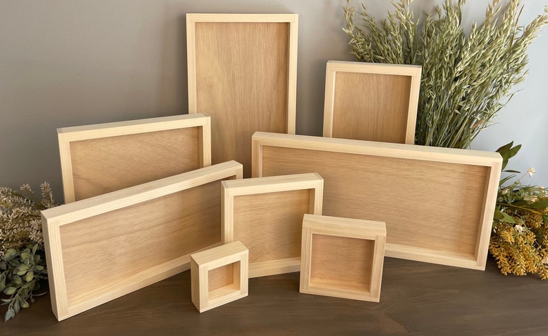 Puede incluir: Un conjunto de siete marcos de fotos de madera en varios tama&ntilde;os, todos con un acabado de madera natural. Los marcos est&aacute;n dispuestos en un patr&oacute;n escalonado sobre una superficie de madera.