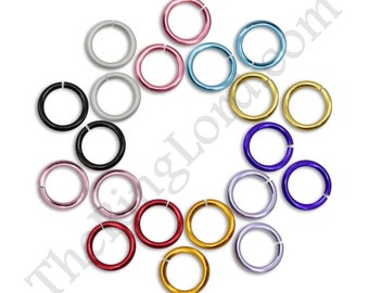 May include: A collection of colorful jump rings in various shades, including black, silver, pink, blue, gold, and purple. These metal rings are arranged on a white background, ideal for jewelry making and crafts.