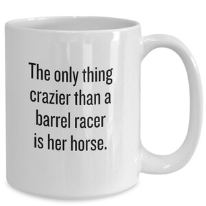 May include: White ceramic coffee mug with black text that reads "The only thing crazier than a barrel racer is her horse."