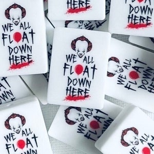 May include: A collection of rectangular white tiles featuring a graphic print of a clown face, a red balloon, and the text WE ALL FLOAT DOWN HERE in black and red lettering. Each tile has a smooth finish and displays the same horror-themed design.