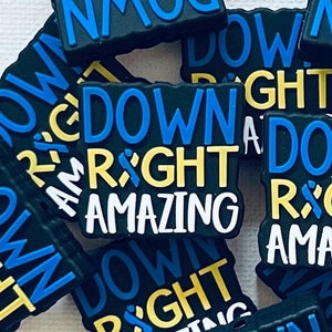 May include: A close-up of a pile of black, blue, and yellow shoe charms with the text "Down Right Amazing".