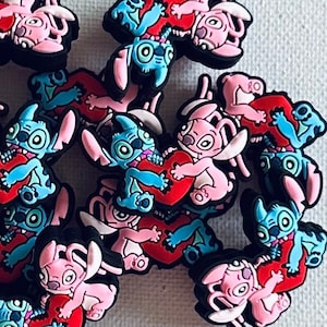 May include: A group of 15 pink and blue cartoon character charms, each holding a red heart. The charms are made of plastic and have a glossy finish.