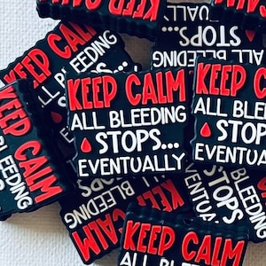 May include: A close-up of a pile of black and red silicone shoe charms with the text "Keep Calm All Bleeding Stops... Eventually".