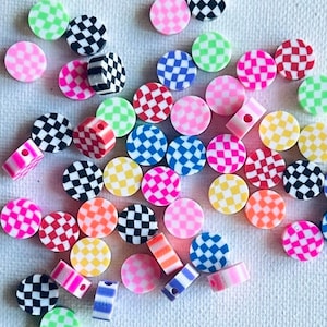 May include: A collection of colorful checkerboard patterned round beads. The beads are made of plastic and have a variety of colors, including pink, green, blue, red, yellow, and black.