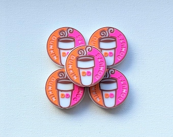 以下が含まれることがあります： 茶色の液体が入った白いコーヒーカップと、オレンジとピンクの「Dunkin Donuts」の文字が描かれた5つの円形シューズチャーム。各チャームのカップには「DD」の文字があり、背景はオレンジとピンクに分かれています。