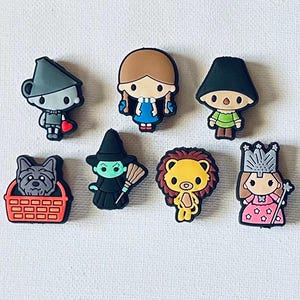 May include: Set of 8 Wizard of Oz themed shoe charms. The charms are made of rubber and feature characters from the movie, including Dorothy, the Tin Man, the Cowardly Lion, the Wicked Witch of the West, and Toto.
