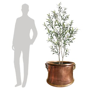 May include: An olive tree in a copper-colored planter. The tree has green leaves and small black olives. The planter has two handles and a wide base. The tree is tall and slender.