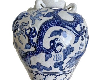 May include: A white and blue ceramic vase with a dragon design. The vase features a detailed blue dragon wrapping around the body, with cloud and wave motifs. It has two handles and a cracked glaze finish.