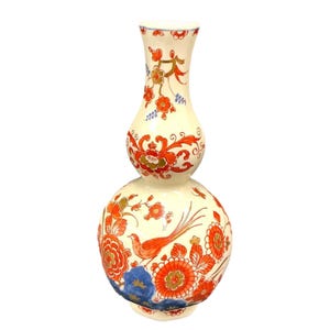 May include: A white ceramic vase with a double gourd shape. The vase is decorated with a floral pattern in shades of red, orange, blue, and gold. The vase is approximately 12 inches tall.