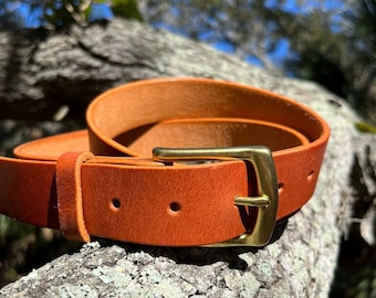 May include: A brown leather belt with a brass buckle. The belt is a warm shade of brown and appears to be made of high-quality leather. The brass buckle adds a touch of elegance to the belt's design.