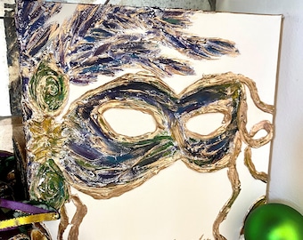 May include: A painting of a purple and gold masquerade mask with green accents on a white canvas. The painting is signed "Lauren Lee" in the bottom right corner.