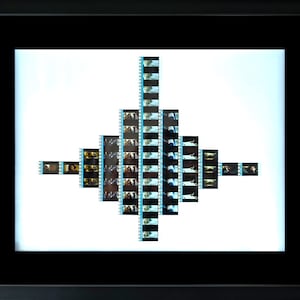 May include: A framed artwork featuring film strips arranged in a geometric pattern. The strips, with a blue border, display a series of images. The frame is black, and the background is white, creating a striking contrast.