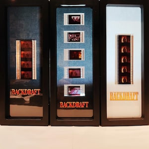 Peut inclure: Trois cadres de cellules de film représentant des bandes de film du film Backdraft. Les cadres sont noirs, bleus et blancs avec le titre "Backdraft" en lettres rouges et dorées.