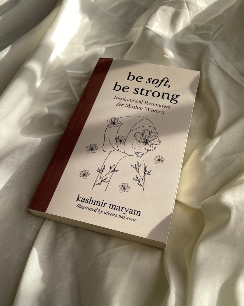 May include: A book titled "be soft, be strong" with a line drawing of a woman wearing a headscarf and flowers. The subtitle is "Inspirational Reminders for Muslim Women". The book is by kashmir maryam and illustrated by aleena masroor.