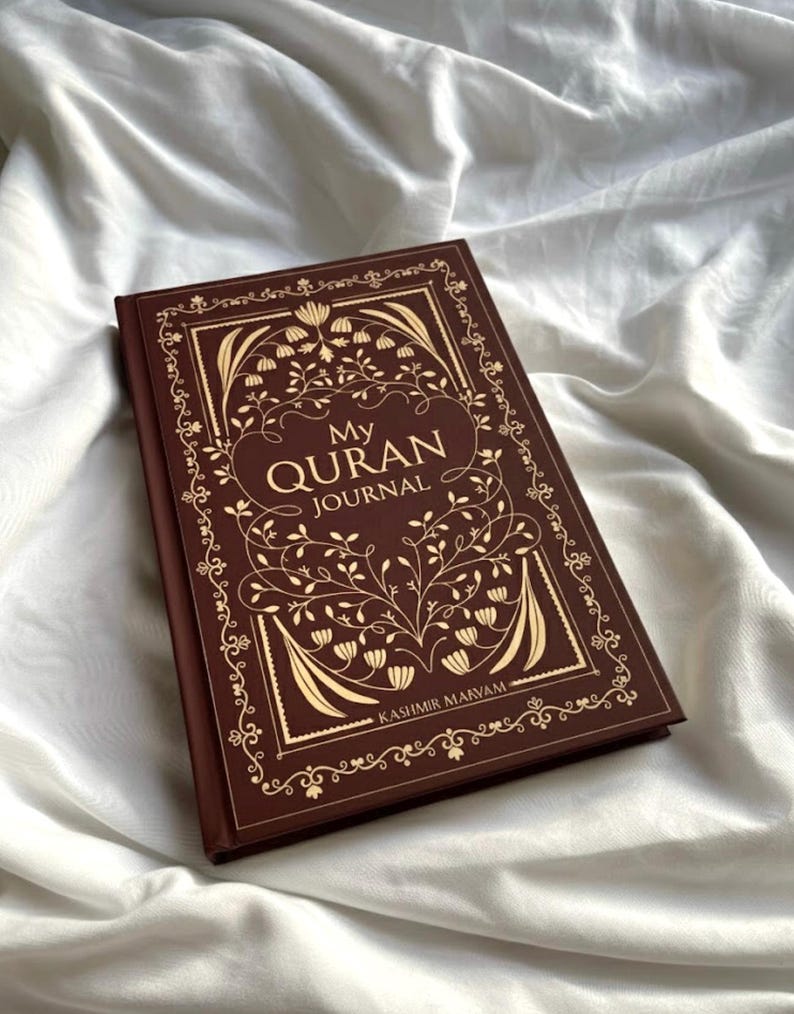 May include: A brown journal with gold floral designs and the text "My Quran Journal." The cover features an ornate border and the name "Kashmir Marvam" at the bottom. The journal is set against a white, textured background.