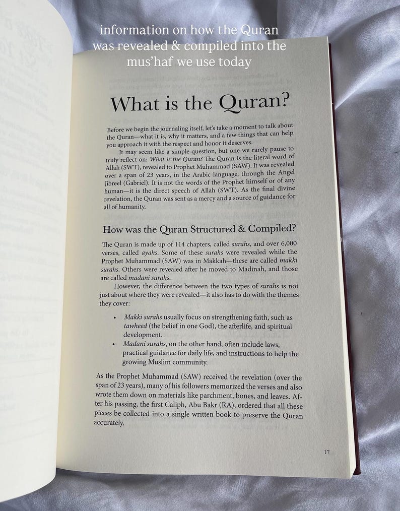 May include: Open book with text about the Quran, including its revelation and compilation. The pages are white with black text, and the book is open to a section titled "What is the Quran?" and "How was the Quran Structured & Compiled?"