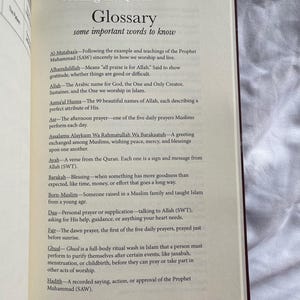 May include: Open book with a glossary of Islamic terms. The page displays a list of words and their definitions, including "Alhamdulillah," "Allah," and "Asma'ul Husna." The text is in black font on a cream-colored page.