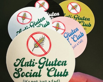 May include: A collection of round stickers with the text "Anti-Gluten Social Club" and the phrase "(it's not just a fad)". The stickers are in various colors, including white, black, pink, and yellow, with a red "no gluten" symbol.