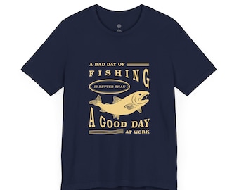 May include: Navy blue t-shirt with a gold graphic of a fish and the text "A bad day of fishing is better than a good day at work." The shirt is made of a soft material.
