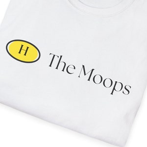 May include: White t-shirt with a yellow oval containing the letter "H" and the text "The Moops" printed in black.