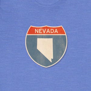 May include: A blue t-shirt with a vintage-style highway sign featuring the state of Nevada and the text "NEVADA".