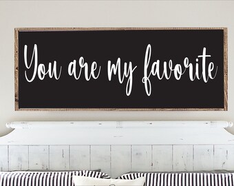 May include: A black wooden sign with white lettering that reads "You are my favorite". The sign is hanging above a white wooden headboard.