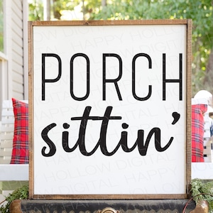 May include: A white wooden sign with a brown frame, hanging on a porch swing. The sign reads "PORCH sittin'" in black lettering.