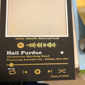 May include: A black and gold framed print with a white heart and a Spotify music player icon. The text reads "Hail Purdue All-American Marching Band Featuring Amanda Coy - Golden Girl #31" and "Class of 2022".