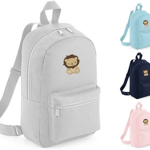 May include: A grey canvas backpack with a small embroidered lion on the front. The backpack has two zipped compartments and adjustable straps. The backpack is also available in blue and pink.