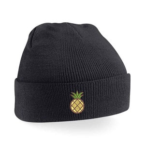 May include: Black knitted beanie with a yellow pineapple embroidered on the front.