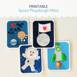 Puede incluir: Cuatro alfombras de plastilina imprimibles con temática espacial. Cada alfombra presenta una imagen diferente con temática espacial: un cohete, un astronauta, una luna con una bandera y planetas. Las alfombras están impresas en cartulina blanca y tienen un fondo azul.