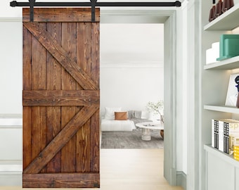 May include: A rustic, wooden barn door with a dark brown finish and a distinctive Z-shaped brace design. The door hangs from a black metal track, adding a touch of industrial style to the interior space. The door is made of wood and is a warm brown color.