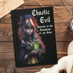 Puede incluir: Diario negro con una mujer de cabello oscuro y ojos verdes que sostiene una botella de poción verde. El texto en el diario dice "Chaotic Evil Anarchy is the Symphony of my Soul."