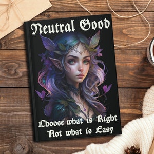 May include: A black journal with a purple and green illustration of a fairy with the text "Neutral Good Choose what is Right Not what is Easy".