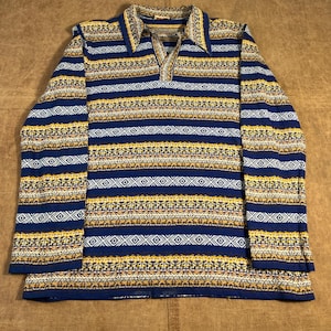 May include: A long-sleeved shirt with a collared neckline and a patterned design. The shirt features horizontal stripes in navy blue, yellow, white, and tan. The fabric appears to be a knit material.