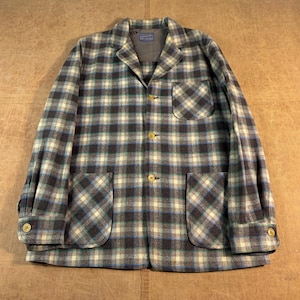 May include: A long-sleeve jacket featuring a plaid pattern in shades of dark blue, light blue, cream, and black. The jacket includes a notched collar, three front buttons, one chest pocket, two lower pockets, and buttoned cuffs with a Pendleton label.