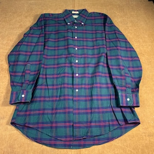 May include: A long-sleeved button-down shirt in a green, navy, and red plaid pattern. The shirt has a button-down collar and white buttons. The fabric appears to be a medium-weight woven material.