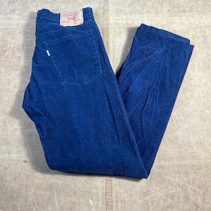 May include: A pair of blue corduroy pants with a classic five-pocket design. The pants feature a Levi's brand patch on the back and a small tag on the back pocket. The corduroy fabric has a ribbed texture.