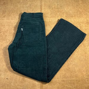 Op de afbeelding: Donkerblauwe corduroy broek met een klassiek ontwerp met vijf zakken. De broek heeft een rechte pijp en een klein wit label op de achterzak. De corduroy stof heeft een geribbelde textuur.