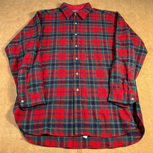 Op de afbeelding: Een button-down shirt met lange mouwen in een klassiek ruitpatroon. Het shirt heeft een rood, groen, marineblauw en geel ruitontwerp. De kraag en manchetten zijn zichtbaar. Het shirt is gemaakt van een zachte, geweven stof.