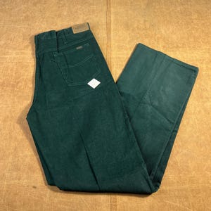 以下が含まれることがあります： ダークグリーンのコーデュロイパンツ。クラシックな5ポケットデザイン。ストレートレッグカットで、バックポケットには小さな白いひし形のタグが付いています。柔らかく、質感のある生地で作られています。