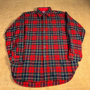 May include: A red, green, and navy plaid flannel shirt with a button-down front and long sleeves. The shirt has a rounded hem and a red collar lining. The plaid pattern is a classic design.