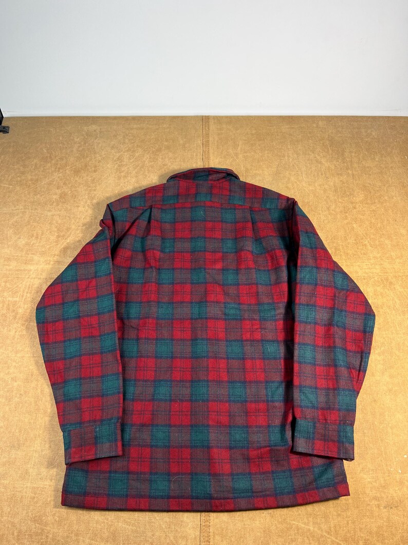 May include: A red, green, and dark blue plaid flannel shirt. The shirt has long sleeves and a button-down front. The plaid pattern is a classic design, with a mix of red, green, and dark blue squares. The shirt is made of a soft, warm material.